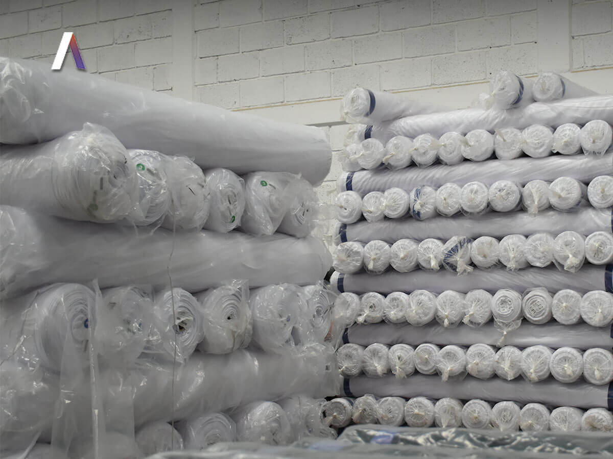 Rollos de tela apilados por familia en la bodega de Arletex
